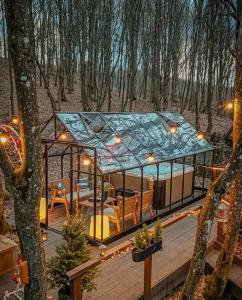 a glass house with a roof on a wooden deck at Montebello Chalet in Porumbacu de Sus