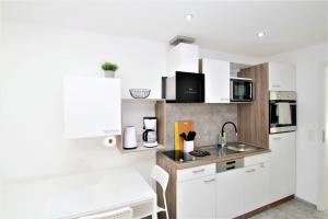 a small kitchen with white cabinets and a sink at Ferienwohnung Glücks-Burg "Stern" in Glücksburg