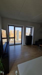 an empty room with large windows and a living room with a couch at Two-story four-room apartment in Copenhagen