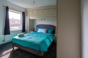 a bedroom with a bed with a blue comforter and a window at Charming 2br Maisonette In Carlisle Center in Carlisle