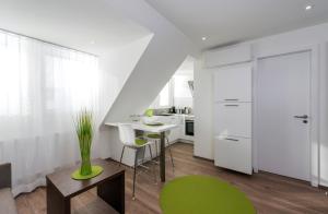 a kitchen with white cabinets and a table and green chairs at apart N serviced apartments in Nuremberg