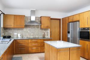 a kitchen with wooden cabinets and a stainless steel refrigerator at Waterfall House in Faial da Terra