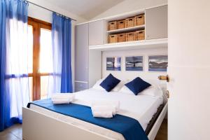 Un dormitorio con una gran cama blanca con detalles azules. en Homey Experience - Attic Panorama, en La Maddalena 6 fotos más