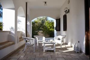 un patio con sillas blancas y una mesa en un patio en Villa Carrubo Peroscia by STHEY, en Padresergio