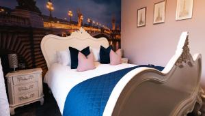 a bedroom with a white bed with blue and pink pillows at St Hildas Complex in Hinderwell