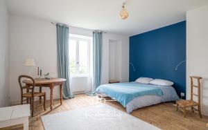 ein Schlafzimmer mit blauen Wänden und einem Bett und einem Schreibtisch in der Unterkunft Maison cosy proche du Mans avec jardin et BBQ - l'instant clef in Parigné-lʼÉvêque