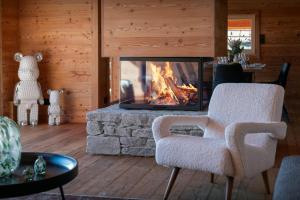 a living room with a fireplace and a chair at Chalet Ellambra - OVO Network in Combloux