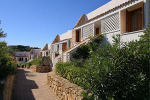 a row of white houses with plants on a street at Capo Ceraso Family Resort in Costa Corallina