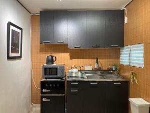 a kitchen with black cabinets and a sink and a microwave at YongDamJae in Seoul