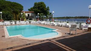 a swimming pool with chairs and a table and water at Residence La Bricola LB 238 in I Casoni