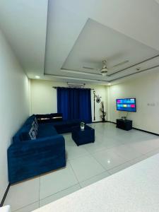 a living room with a blue couch and a flat screen tv at Deluxe suite in bahria heights 1 rawalpindi in Rawalpindi