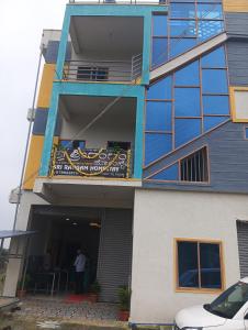 Ein Mann steht auf dem Balkon eines Gebäudes in der Unterkunft Homestay Rooms& Food Sri Ranga Homestay in Belūr