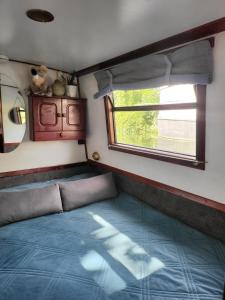 Una cama en una habitación pequeña con ventana. en Comfy Canal in Little Venice for Family & Friends, en Londres