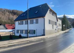 a white house with a blue roof on a street at Apartament KROPELKA in Piechowice