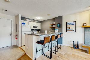 Una cocina con barra con taburetes y refrigerador. en Okemo Mountain Lodge A208, en Ludlow