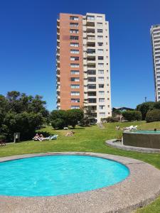a swimming pool in a park with a tall building at Departamento ideal para relajarse y descansar in Concón