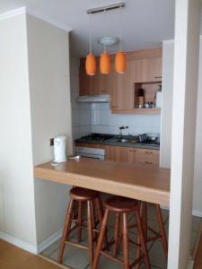 a kitchen with a wooden counter and stools at Departamento ideal para relajarse y descansar in Concón