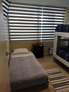 a bedroom with a bed and a window with blinds at Departamento ideal para relajarse y descansar in Concón