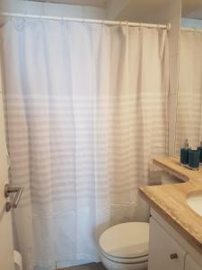 a bathroom with a white shower curtain and a toilet at Departamento ideal para relajarse y descansar in Concón