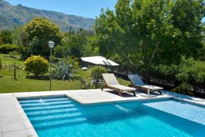 a swimming pool with two chairs and a table at Casa Almendro-Chumamaya-Villa de Merlo in Country Club Chumamaya