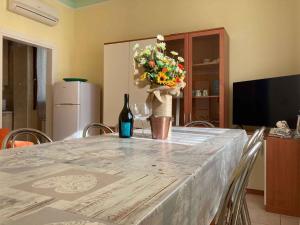 a table with a bottle of wine and a flower arrangement at Apartment in Rosolina Mare 3 in Rosolina Mare