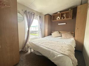 a small bedroom with a bed and a window at Harwich - Caravan - Sleeps 10 - Garden - Pool in Harwich +16 photos