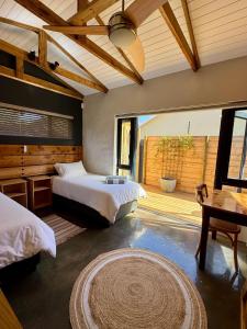 a bedroom with two beds and a table and a rug at Modern Cosy Apartment in Plettenberg Bay