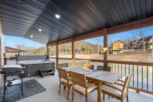 eine abgeschirmte Veranda mit Tisch und Grill in der Unterkunft Tall Timbers Retreat w Free Daily Tickets-Water Views-Community Indoor Pool-Bunk Room-Pvt Hot Tub in Hollister