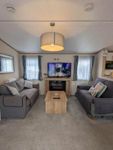 a living room with two couches and a tv at BEAUTIFULLY PRESENTED CARAVAN DOG FRIENDLY on AWARD WINNING SHOREFIELD COUNTRY PARK Entertainment passes and linen included in Milford on Sea