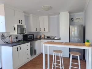 une cuisine avec des armoires blanches et un comptoir avec des tabourets dans l'établissement Be'landre Courtyard Cottage, au Cap