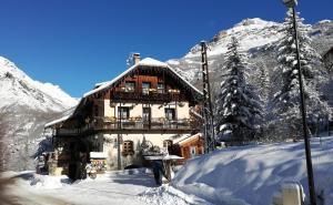 a building in the snow in front of a mountain at Gîte Auberge La Blanche in Pelvoux