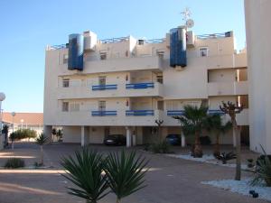 a large white building with palm trees in front of it at Apartamento en La Calma in Playas de Orihuela