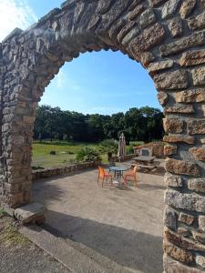 an arch in a stone wall with a table and chairs at Auberge des Quatre Moulines in Le Longeron
