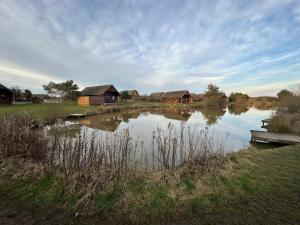 a lake with houses and a boat in the water at 32 Cherry-Lodge-Tranquil-Hot Tub-Fishing Lake-7m to beach in Garton +23 photos