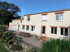 a building with a patio with a table and chairs at Auberge des Quatre Moulines in Le Longeron