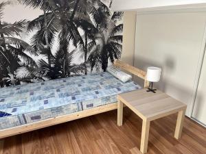 a bedroom with a bed with a table and a palm mural at Auberge des Quatre Moulines in Le Longeron