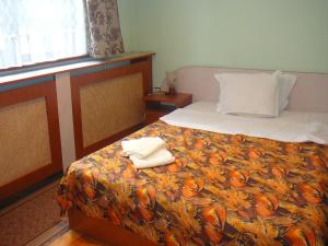 a bedroom with a bed with two towels on it at Къща за гости Типик in Bansko