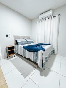 a white bedroom with a bed and a window at Apto em condomínio, vista lagoa in Três Lagoas