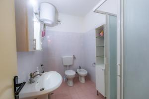 a white bathroom with a toilet and a sink at Lovely Apartment with terrace in Porto Azzurro