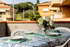 a table with plates and a vase of flowers on it at Lovely Apartment with terrace in Porto Azzurro