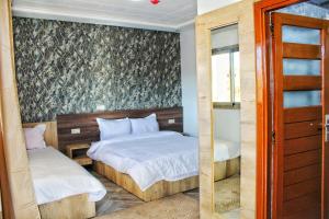 a bedroom with two beds and a sliding glass door at Palmiers Hôtel Club in Er Rachidia