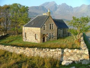 an old stone house on a hill with a stone wall at Torrin Bunkhouse in Torrin