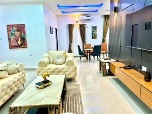 a living room with couches and a flat screen tv at VIN-RUES Apartment and Suites in Benin City