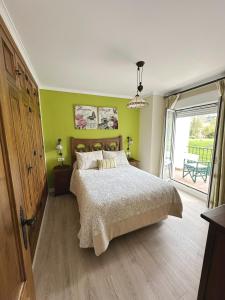 Un dormitorio con una cama con paredes verdes y una ventana en El mirador de El Bosque, en El Bosque
