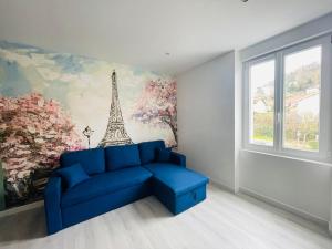 a blue couch in a room with a mural of the eiffel tower at Éclat St Romain n3, duplex - moderne - WIFI - CLIM- proche Vienne in Saint-Romain-en-Gal +2 photos