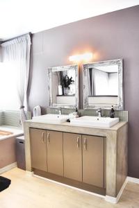 a bathroom with two sinks and two mirrors at 4on Pebbles Holiday Home in Swakopmund
