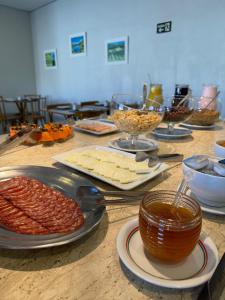 a table with cheese and other food on it at Moinho Itália Hotel in Campos do Jordão