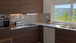 una cucina con armadi marroni, finestra e lavandino di Private V3 Equipped Kitchen a Teixoso
