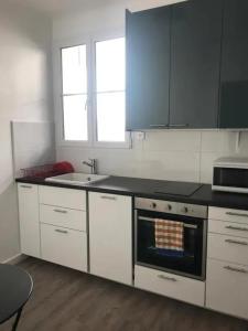 eine Küche mit weißen Schränken und einem Herd mit Backofen in der Unterkunft Appartement confortable à Saint-Jean-de-Luz 45 m² avec cheminée in Saint-Jean-de-Luz