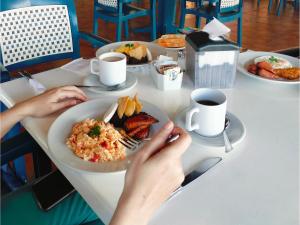 a person sitting at a table with a plate of food at Hotel Cayman Suites in El Garitón